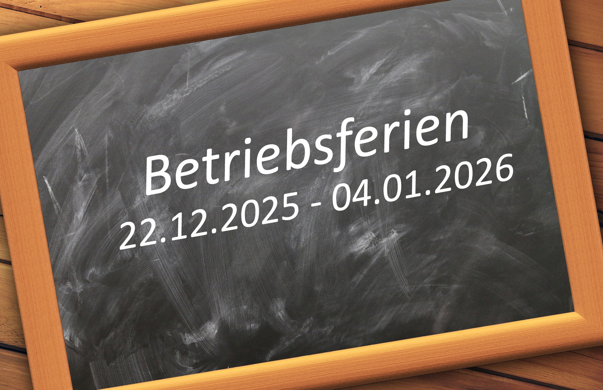 Kreidetafel mit der weißen Aufschrift "Betriebsferien 22.12.2025 bis 04.01.2026"